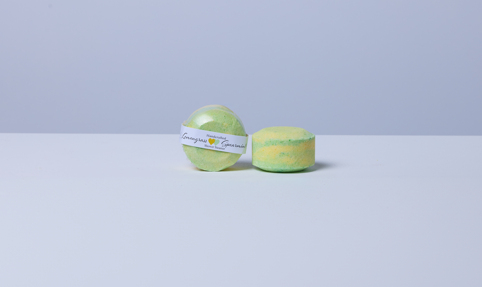 Lemongrass Spearmint Menthol shower steamer by Husk Her Happy shown packaged and unwrapped, handcrafted in yellow and green.